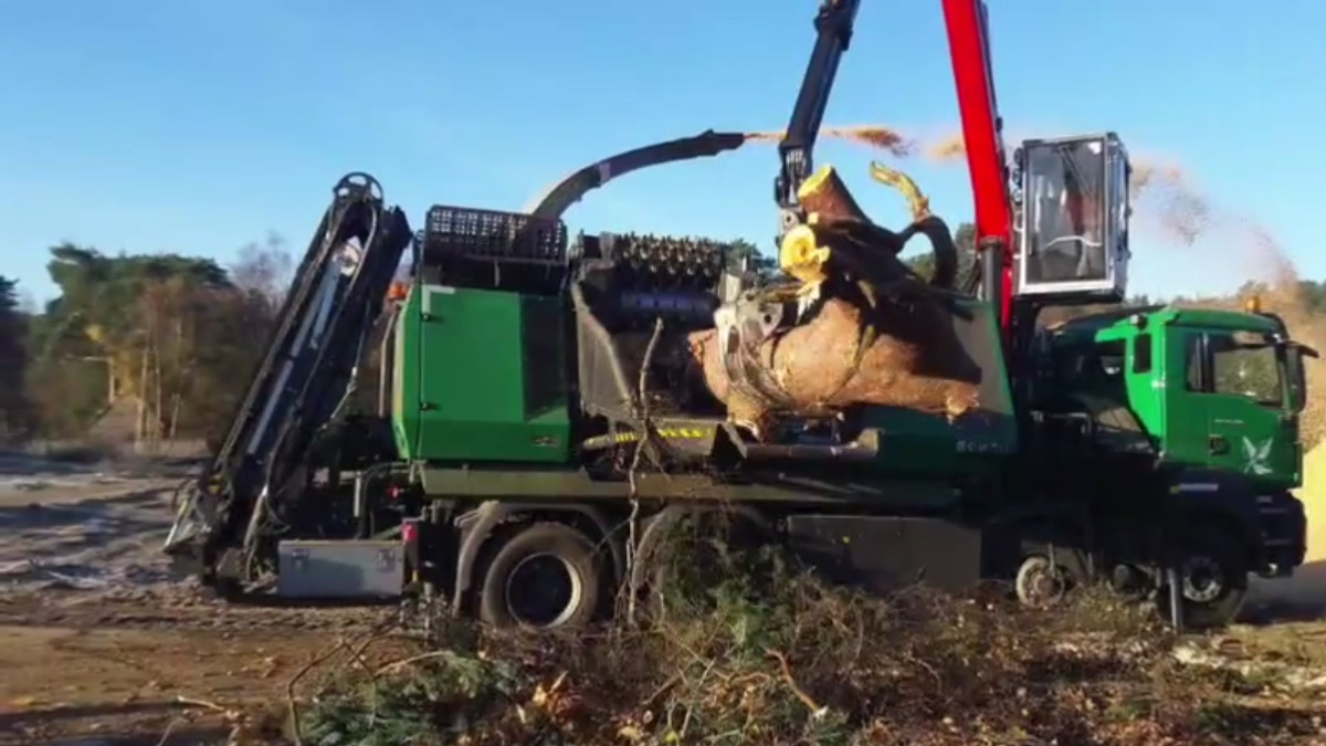 A crane-fed woodchipper in action
