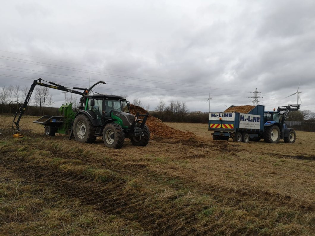 Crane fed chipper clearing wood